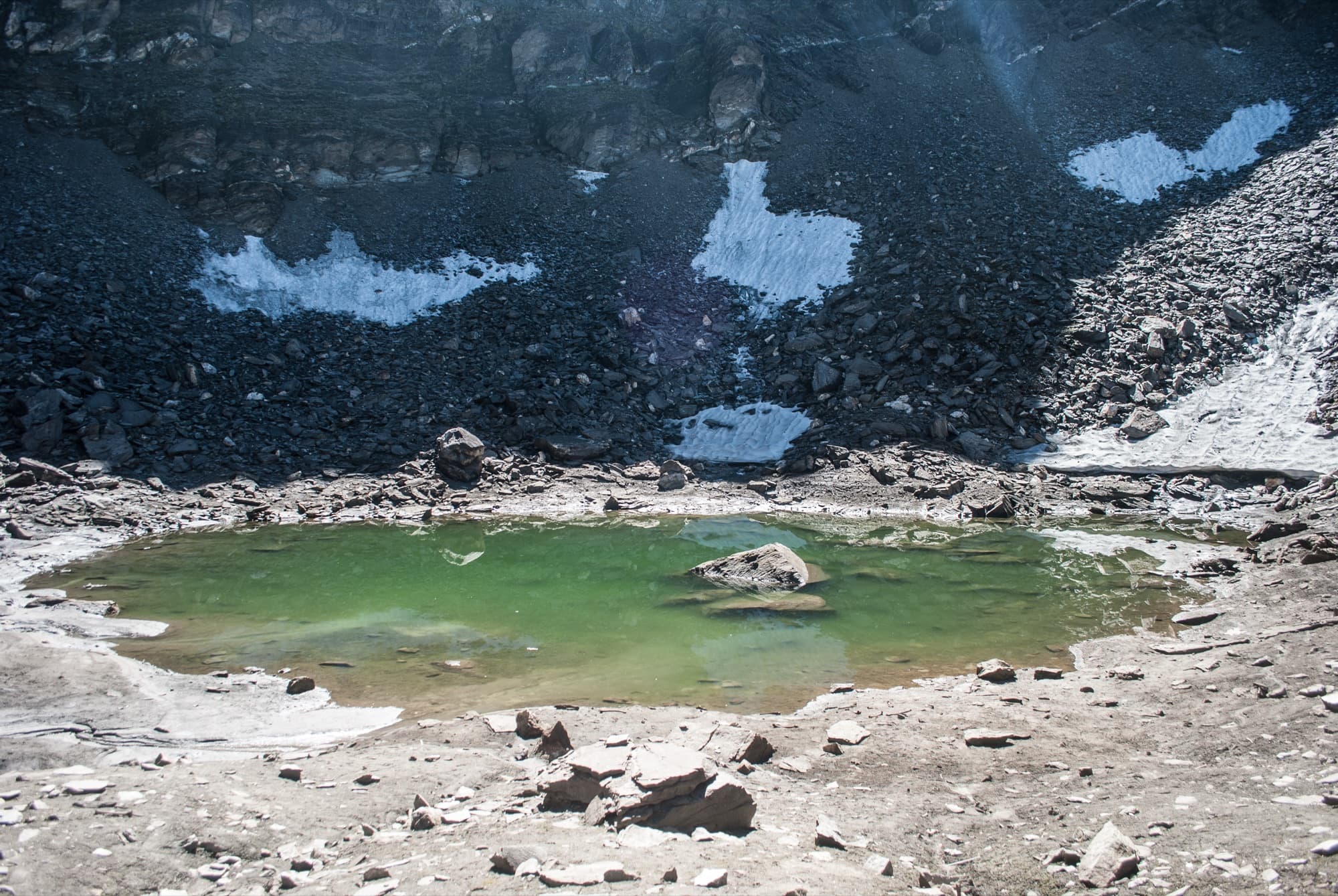 Roopkund, a small glacial lake ringed by scree and snow patches
