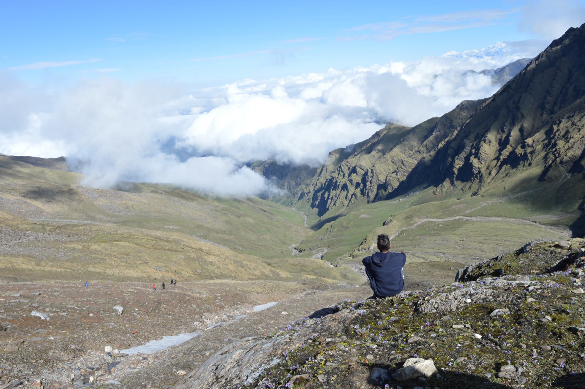 A trekker resting above the green valleys of the Roopkund route